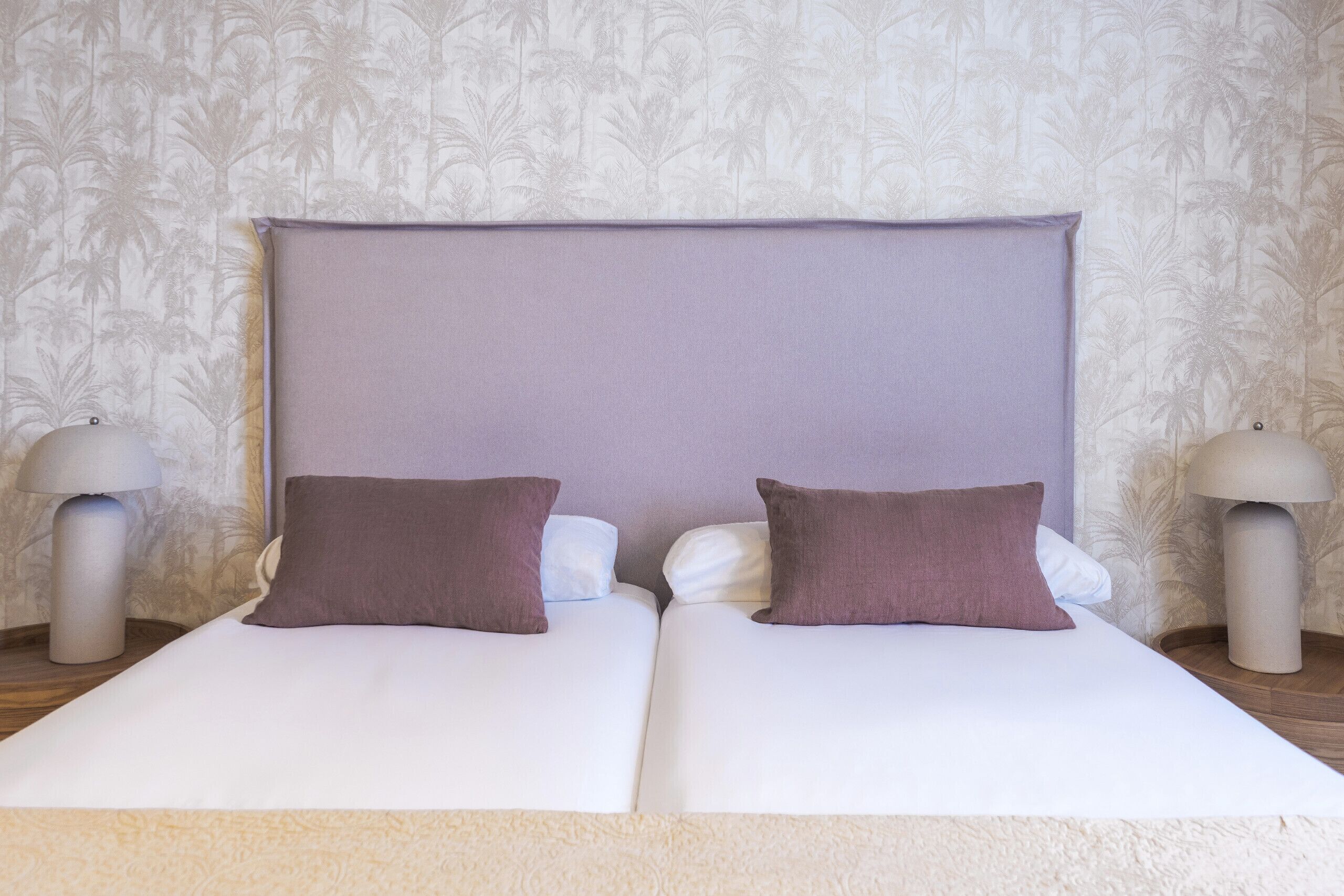 A double bed with two pillows, a headboard, and two bedside lamps.