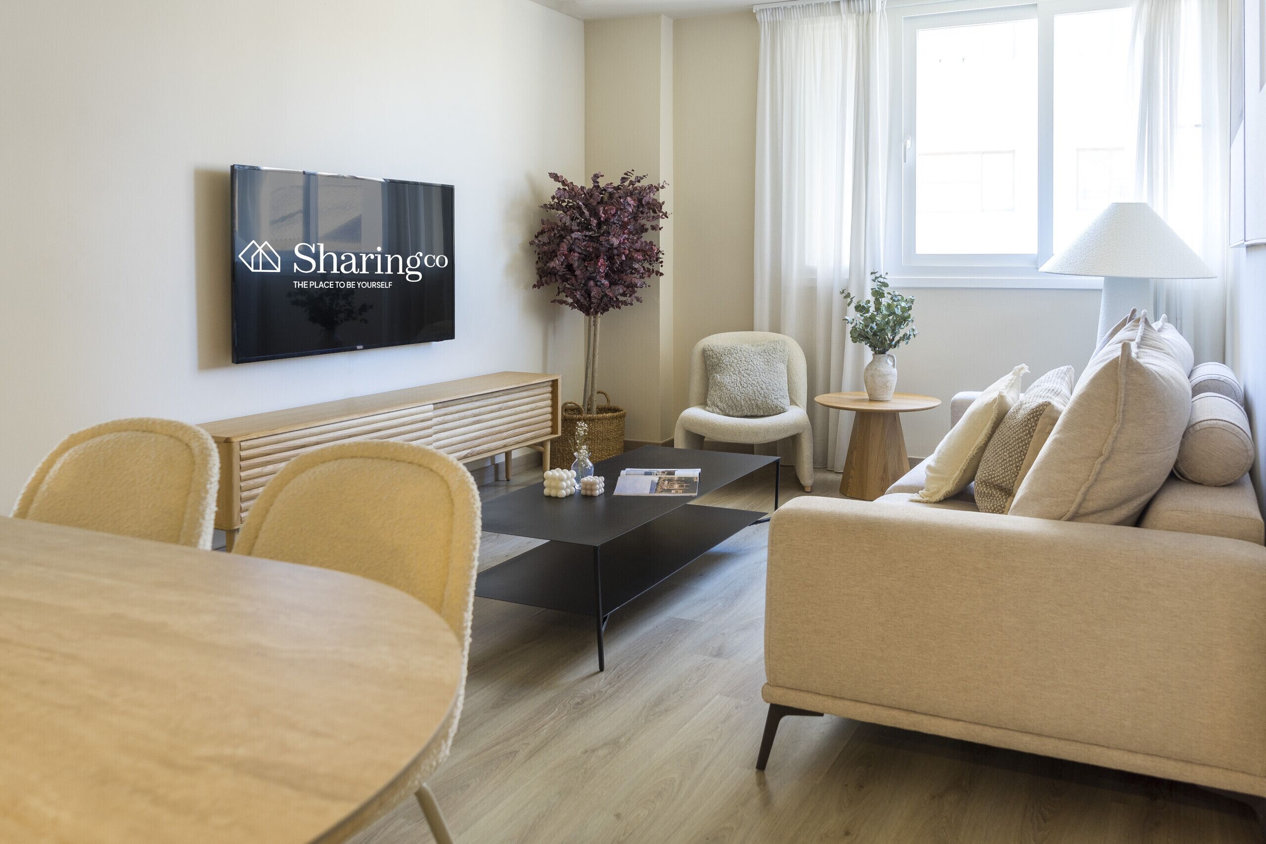 Una sala de estar moderna con un sofá, sillones, una mesa de centro y un televisor montado en la pared.