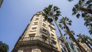 Ein hohes Gebäude mit mehreren Balkonen und Palmen.