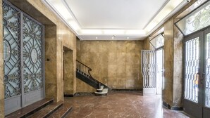 Eine geräumige Lobby mit Marmorboden, einer Treppe und aufwendigen Metallgittern.