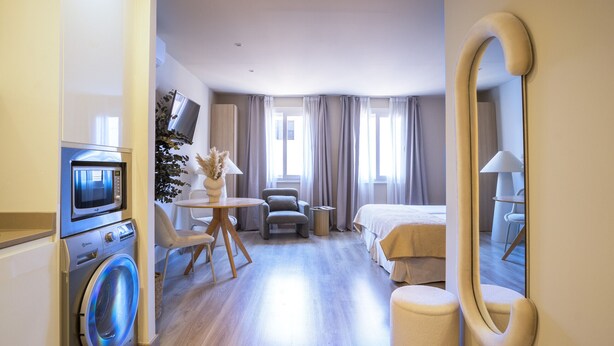 Ein Hotelzimmer mit Waschmaschine, einem Bett, einem Schreibtisch und einem großen Spiegel.