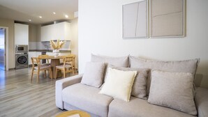 Un salon moderne avec un canapé, une table à manger et des chaises, et une cuisine en arrière-plan.