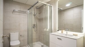 Une salle de bain moderne avec une douche à parois de verre, des toilettes et un meuble-lavabo avec un miroir.