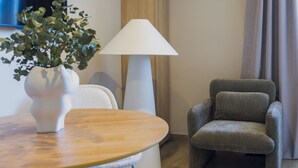 A modern room with a round wooden table, a grey armchair, a white floor lamp, and a white vase with green plants. - Housing Atarazanas by Sharing Co (Málaga)