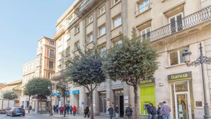 A multi-story building with a green storefront labeled 'Bankia'. - Housing Atarazanas by Sharing Co (Málaga)