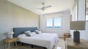 A bedroom with a bed, nightstands, a ceiling fan, a window with a view, and a lamp. - Amazing flat with views & pool by SharingCo  (Marbella)