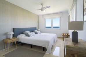 Ein Schlafzimmer mit Bett, Nachttischen, Deckenventilator, Fenster mit Blick und einer Lampe.