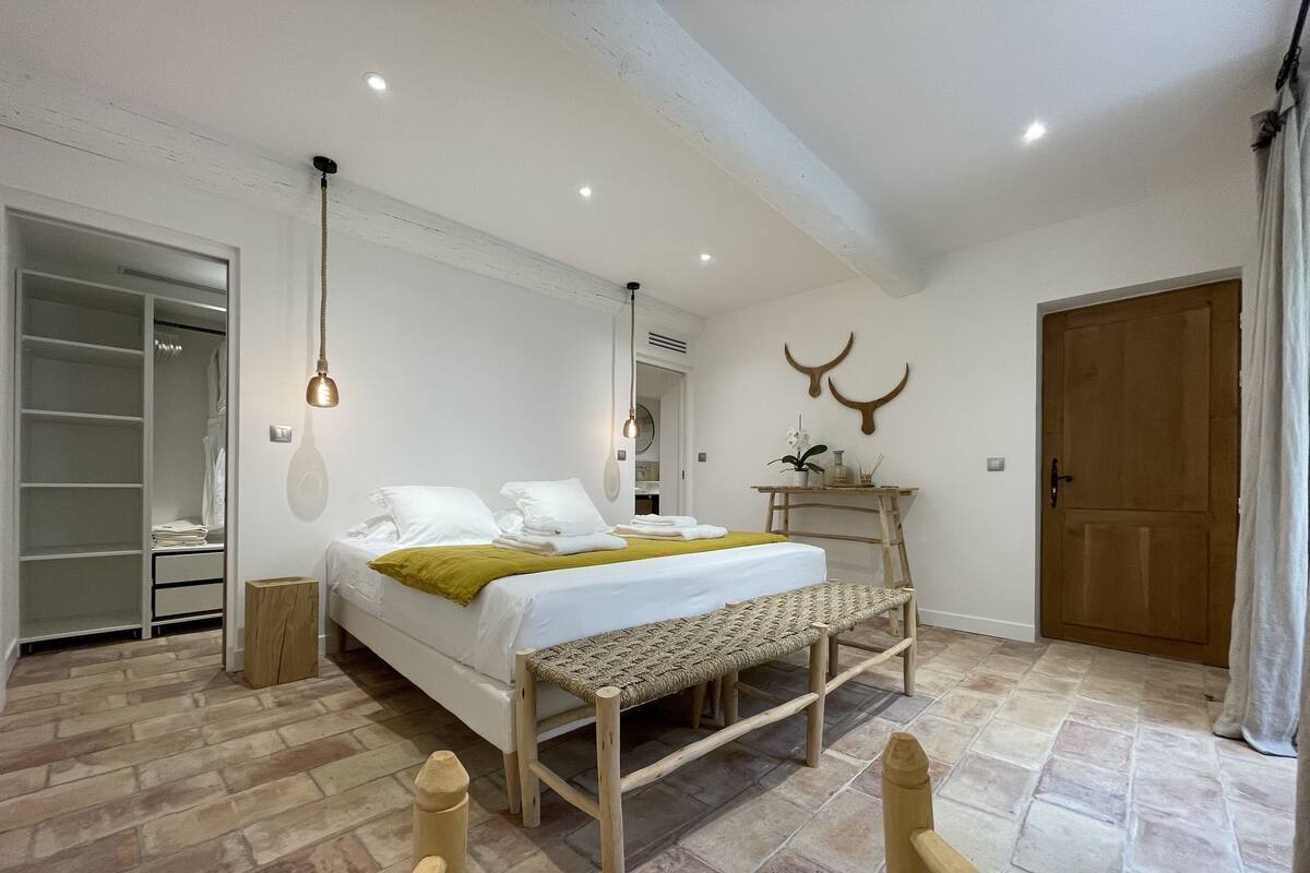 Un dormitorio con cama, mesita de noche, banco de madera y armario.