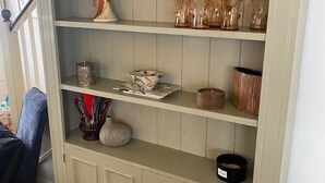A light-colored wooden cabinet with multiple shelves, some with glassware and decorative items.