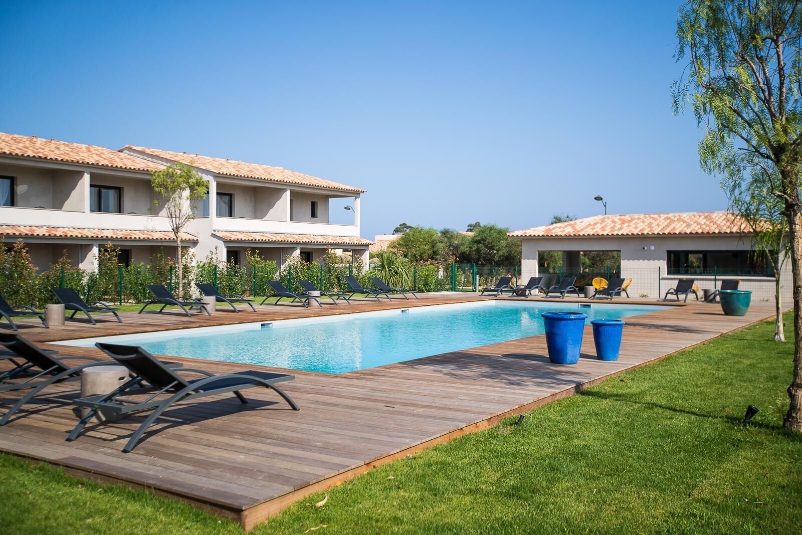 A swimming pool with lounge chairs and a wooden deck.