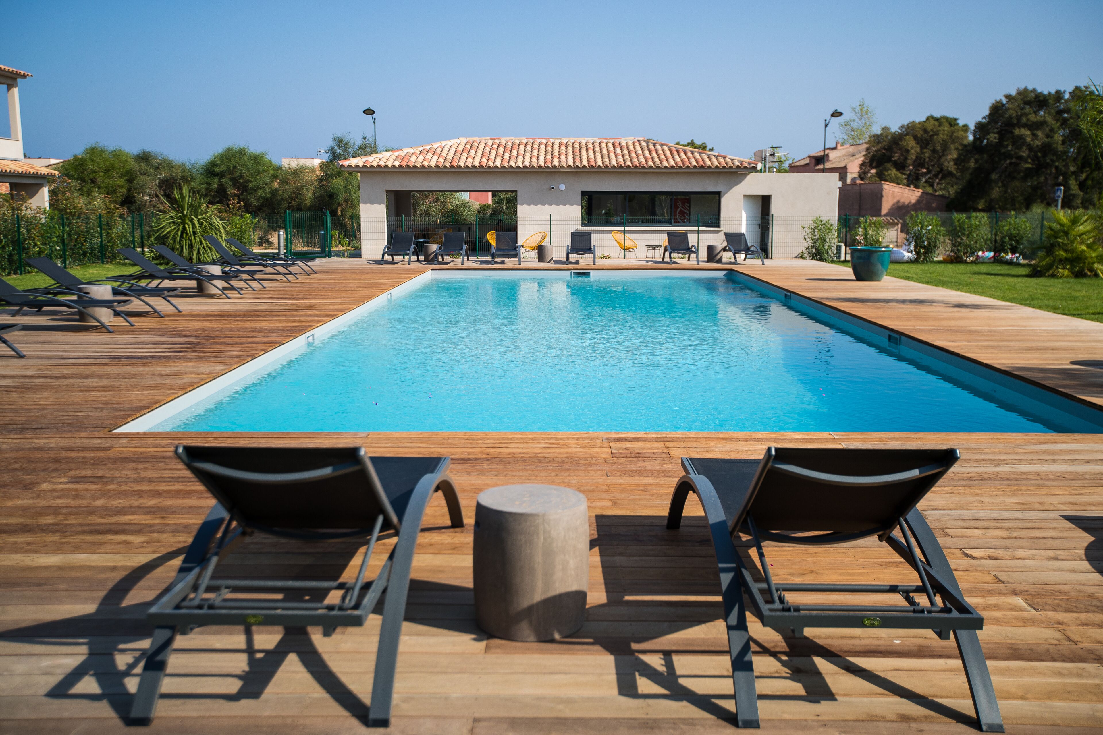 A swimming pool with lounge chairs and a wooden deck.
