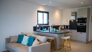 Eine moderne Küche mit einer zentralen Kochinsel, einer Couch mit Kissen und einem Fenster über der Spüle.