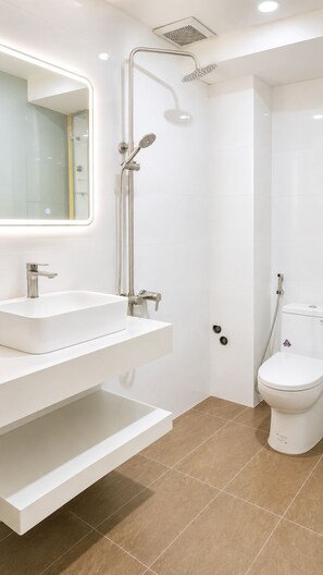 Ein modernes Badezimmer mit Waschbecken, Spiegel und Toilette in Weiß, sowie eine Dusche mit Duschbrause.