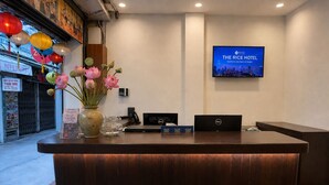 A hotel reception desk with a laptop, a phone, and a vase with flowers. - The Rice Hotel & Tour - 40 Bui Vien No 9 (Ho Chi Minh City)