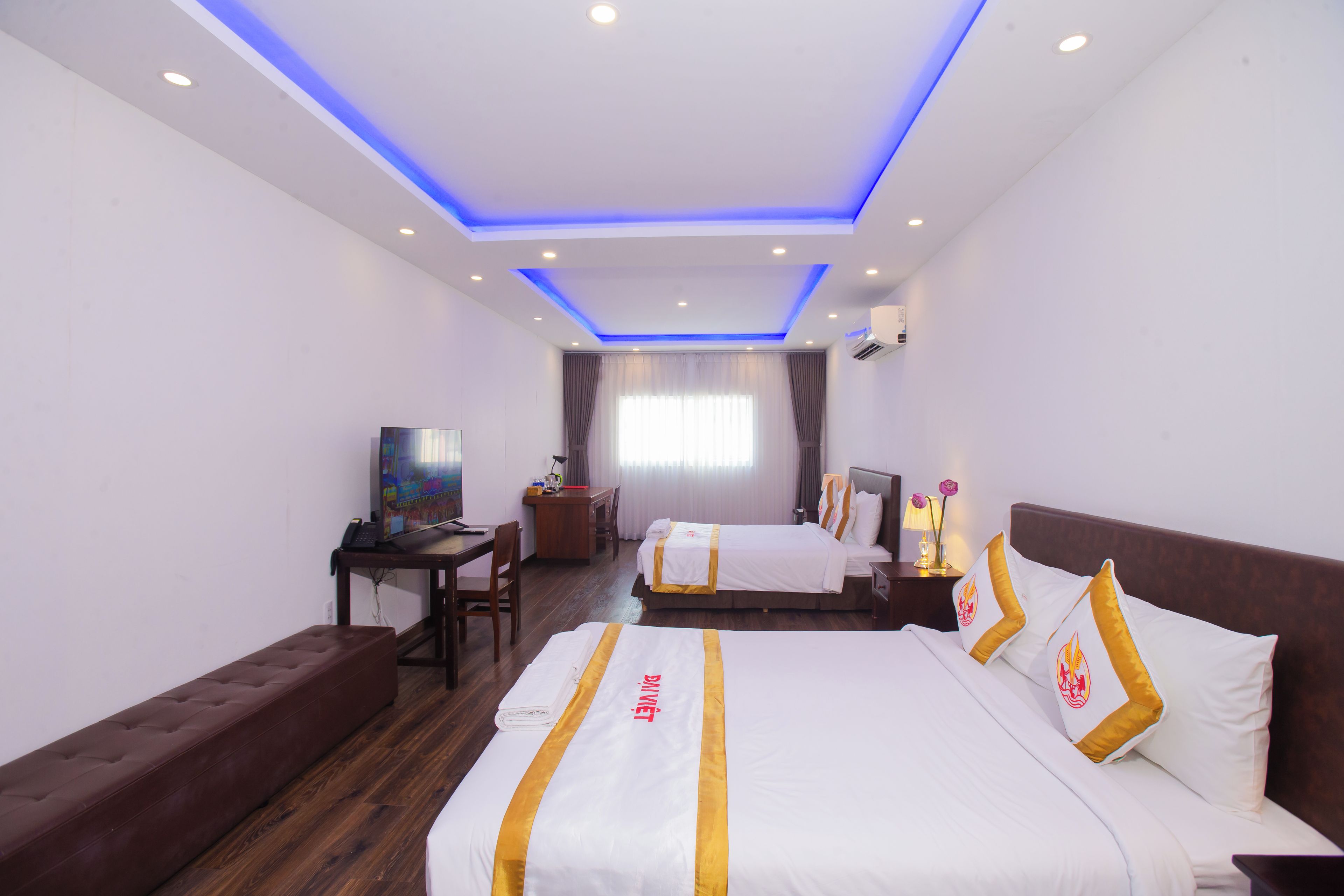 Habitación de hotel con una cama grande, una cama más pequeña, un escritorio y una zona de estar.