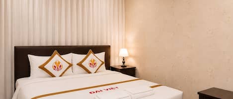 A hotel room with a bed, a nightstand, an air conditioning unit, and a lamp.
