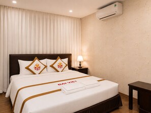 Quarto de hotel com cama, mesa de cabeceira, ar condicionado e abajur.