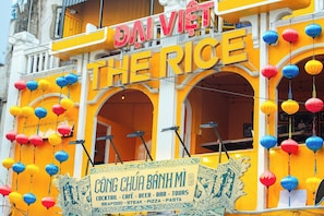Un edificio con un letrero que dice 'DAI VIET THE RICE' y otro letrero debajo que anuncia 'COCTÉLES - CAFÉ - CERVEZA - BAR - TOURS MARISCOS - CARNE - PIZZA - PASTA'.