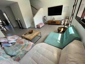 En stue med sofa, sofabord og et fjernsyn hængt på væggen.
