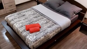 A neatly made bed with a patterned bedspread, two pillows, and two red towels. - Logement Résidence (Antibes)