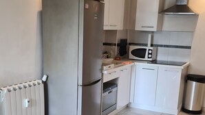 A modern kitchen with a refrigerator, oven, microwave, and a coffee machine. - Logement Résidence (Antibes)