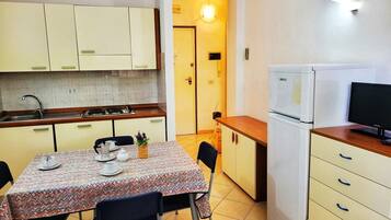 Cocina compacta con una mesa para dos personas, microondas y refrigerador.