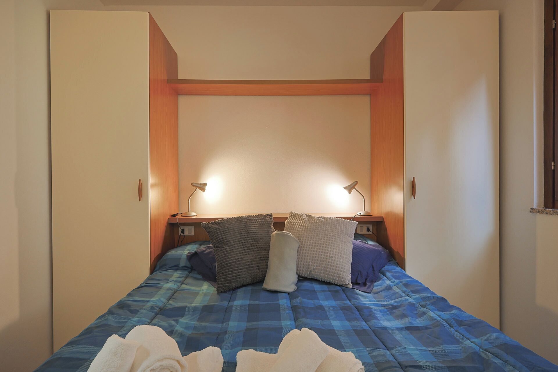 A bedroom with a bed, two bedside lamps, and a window.