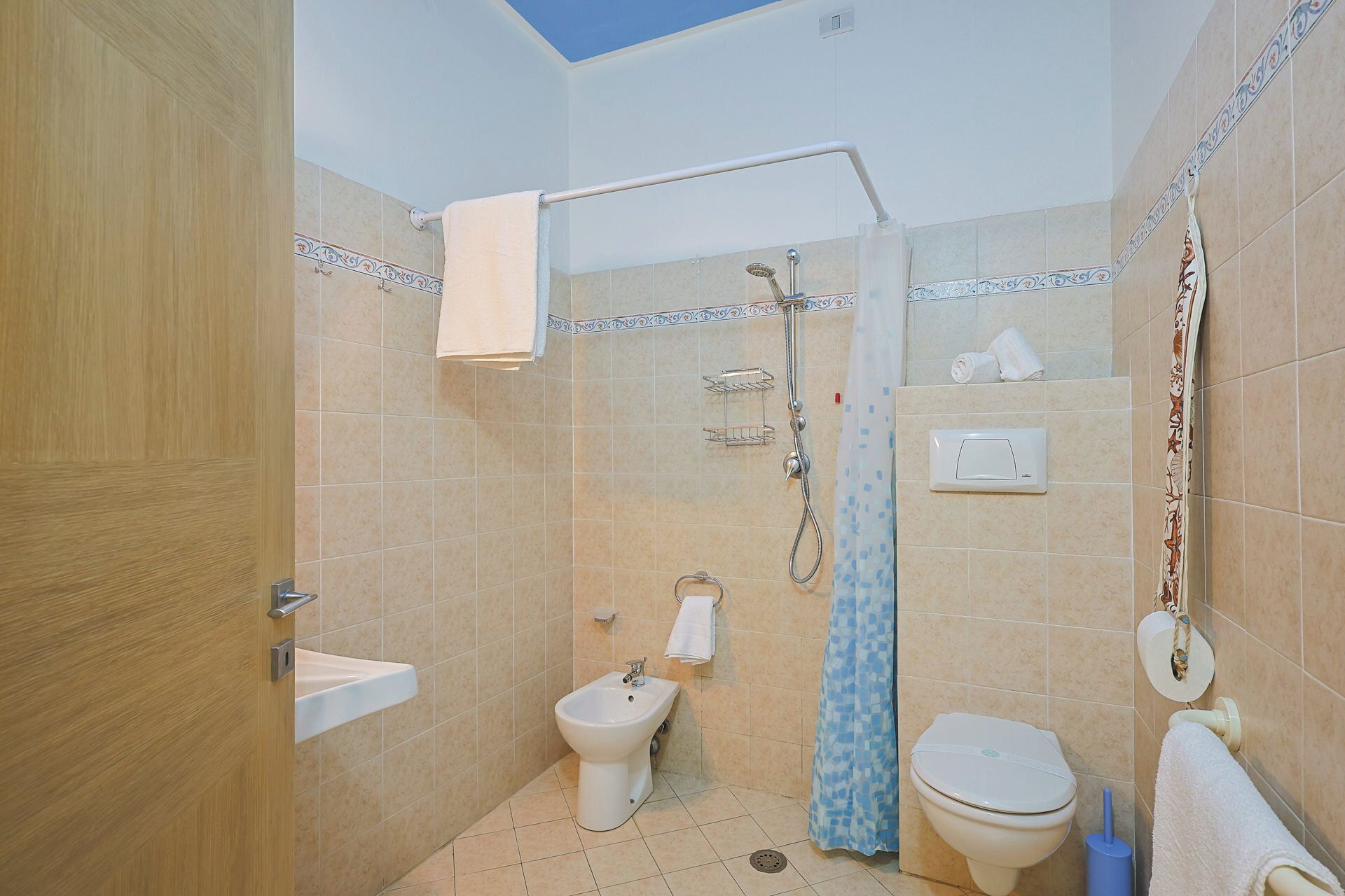 Un bany amb dutxa, dues vàteres, un bidet i un penjador de tovalloles.