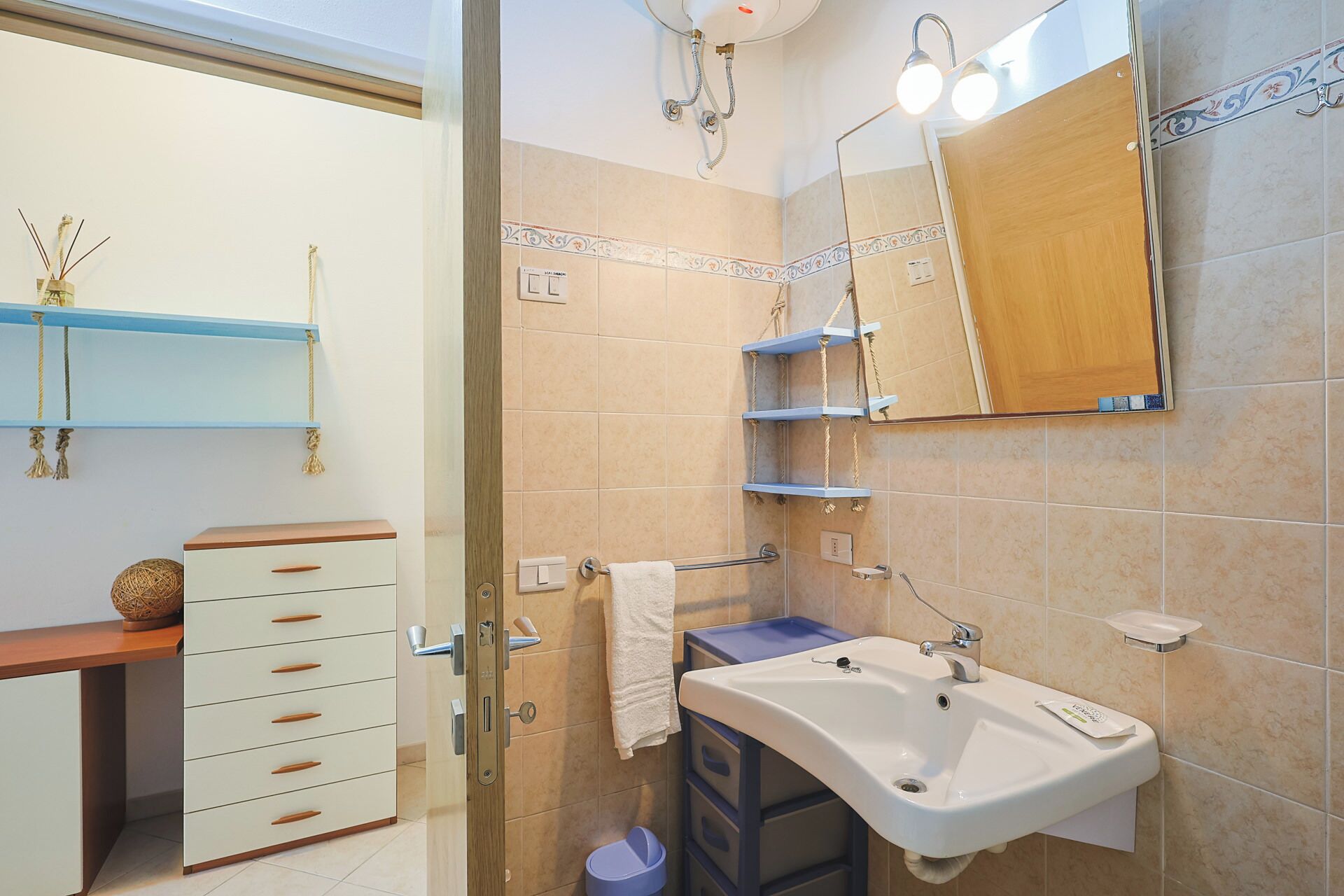 A bathroom with a sink, mirror, towel rack, and shelves.