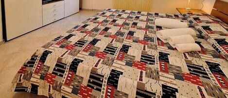 Un dormitorio con cama, armario, ventana con cortinas y mesita de noche con lámpara.