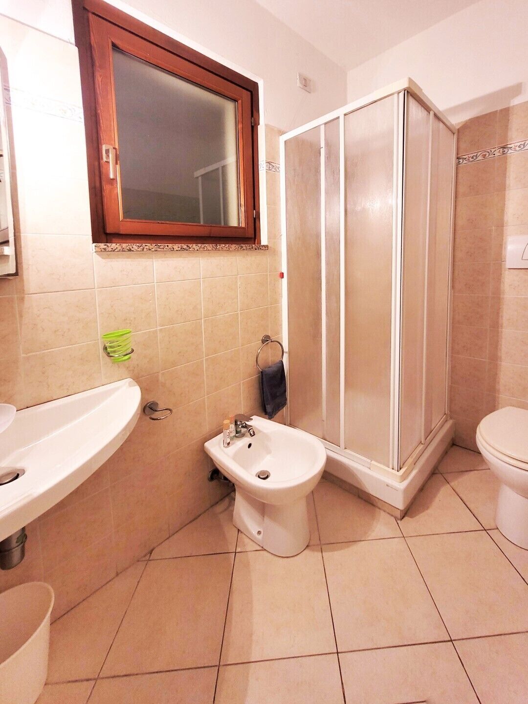 A bathroom with a sink, bidet, toilet, and a shower enclosure.
