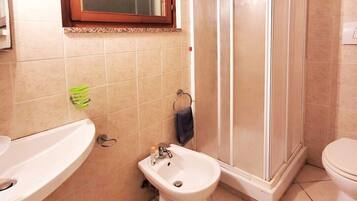A bathroom with a sink, bidet, toilet, and a shower enclosure.