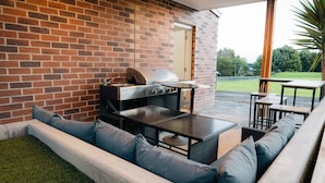 An outdoor patio with a brick wall, a grill, and seating area.