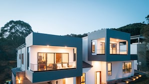 A modern two-story house with a balcony, a garage, and a well-lit entrance.