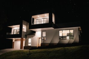 A modern two-story house with a garage, large windows, and a balcony.