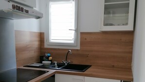 A compact kitchen with a built-in stove, a sink, and a window.