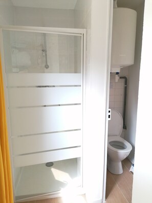 Chuveiro, secador de cabelo, toalhas de banho, papel higiênico