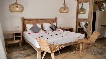 Een slaapkamer met een houten bed, rieten stoelen en een grote spiegel.