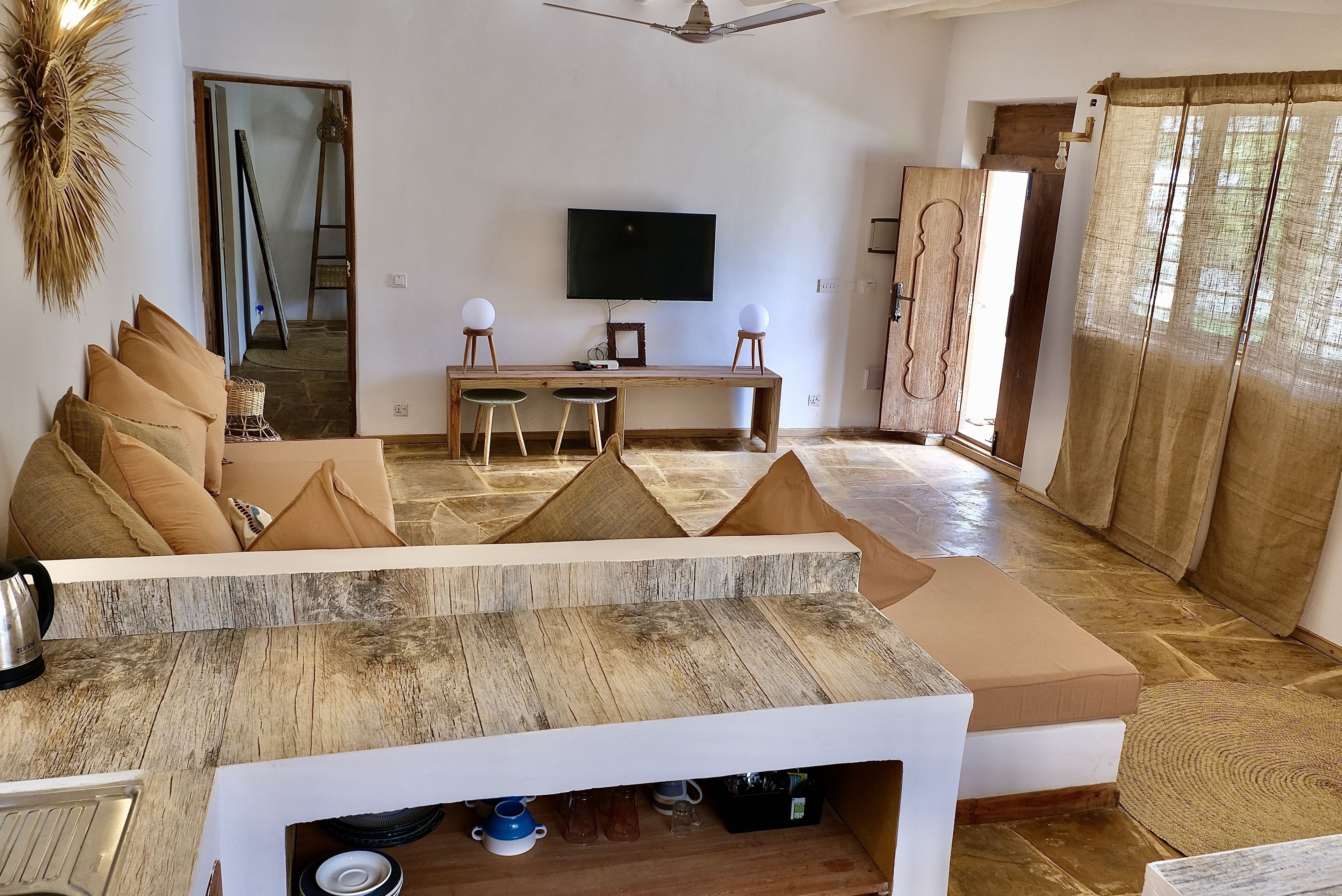 Una sala de estar moderna con un televisor grande, muebles de madera y un sofá con cojines.