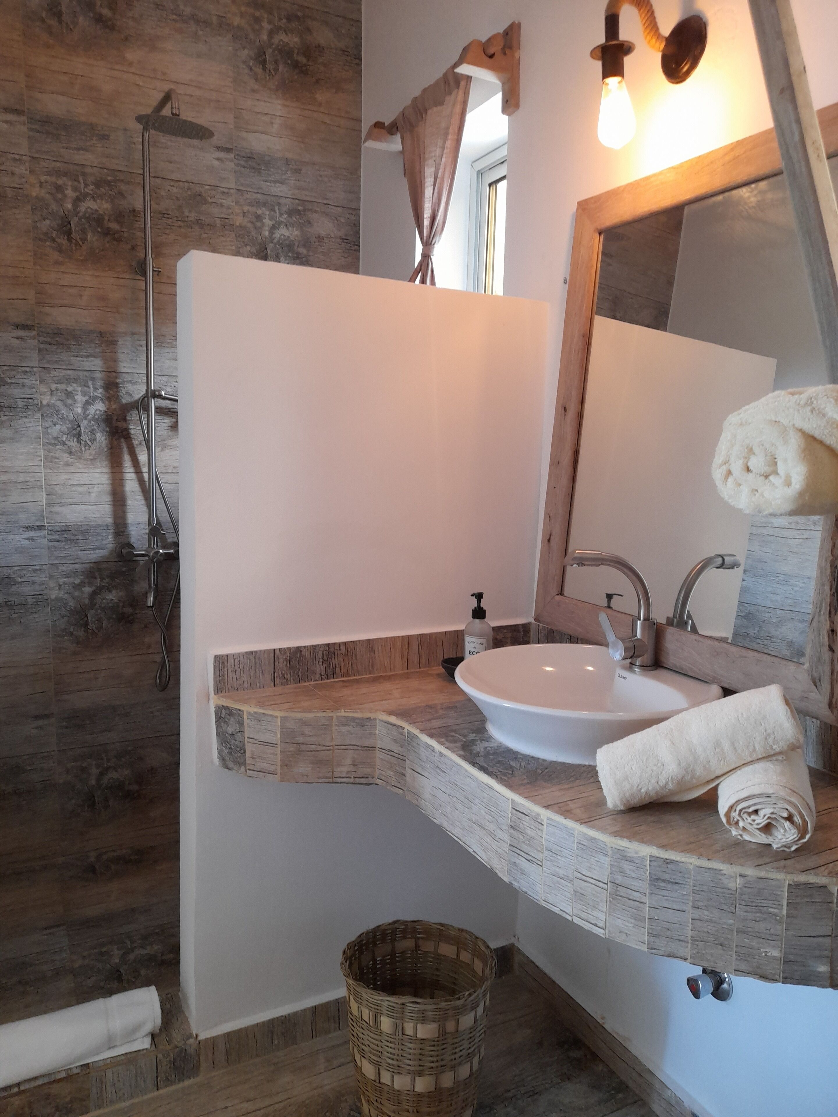 A bathroom with a wooden shower enclosure, a white sink, and a large mirror.