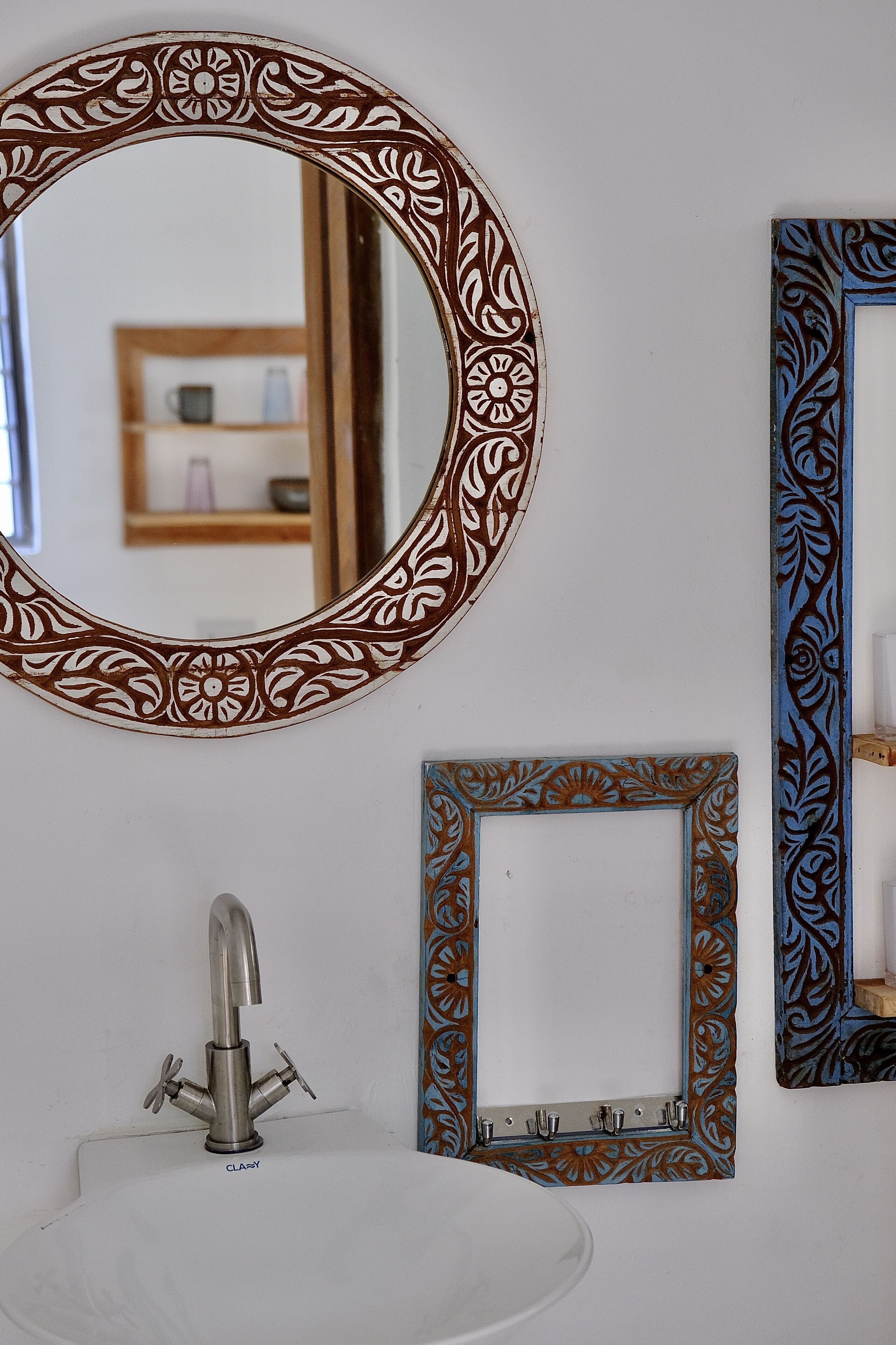 A bathroom with a round mirror, a sink, and two decorative frames.