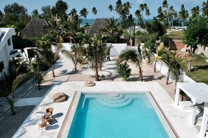 Una piscina rodeada de palmeras y un edificio blanco.
