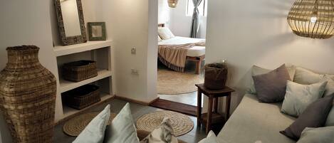 A cozy living room with a sofa, cushions, a large vase, and wicker baskets on shelves.