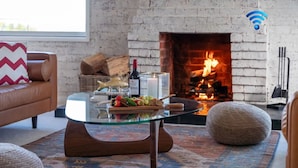 A cozy living room with a fireplace, a glass coffee table with snacks, and a modern sofa. - Halcyon– Breathtaking ocean views (Kiama Heights)