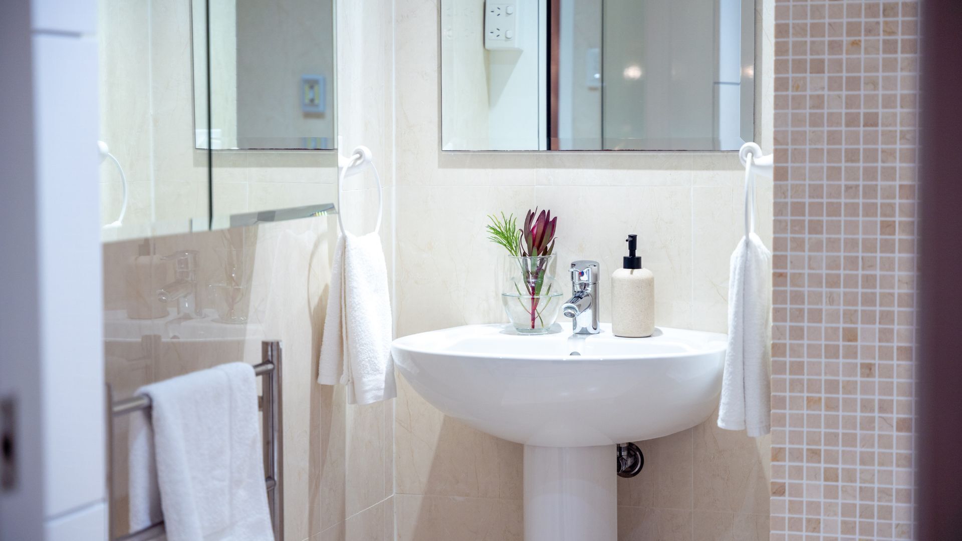 Een badkamer met een witte wasbak, een spiegel en een handdoekhouder.