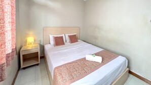 Ein Hotelzimmer mit Bett, Nachttisch, Lampe und einem fenster mit Vorhängen.