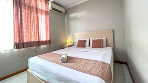 Ein Hotelzimmer mit einem Bett, einem Nachttisch, einer Klimaanlage und einem Vorhangfenster.