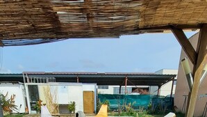 En uteplats med möbler i rotting, en pool och ett takförsett område med en pergola.