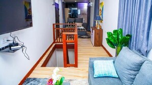 Una sala de estar moderna con un sofá, una silla de madera, un televisor montado en la pared y una planta.