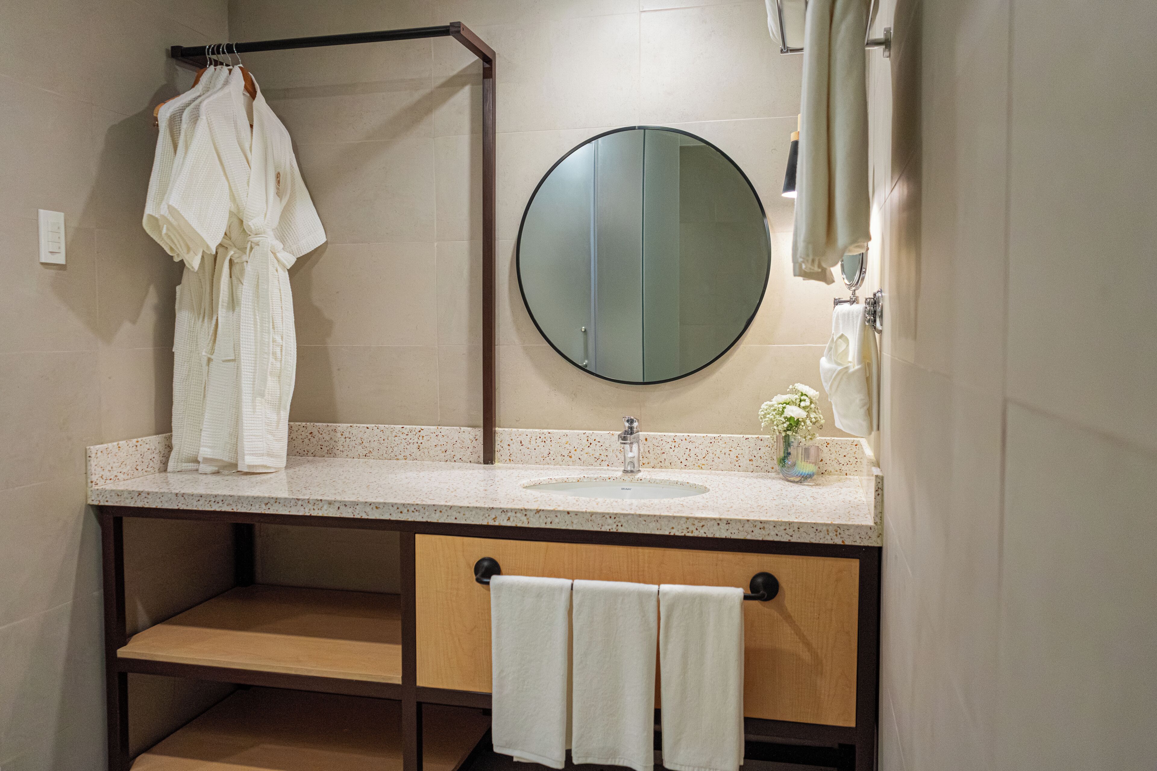 A bathroom with a round mirror, a sink, and a towel rack.